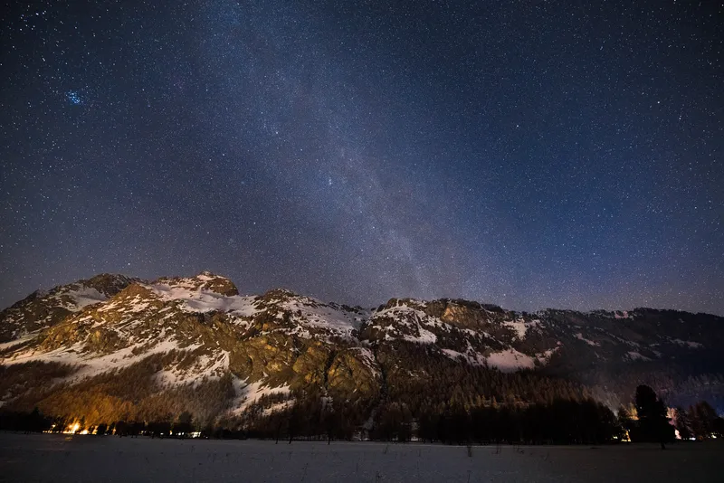 Sternenhimmel mit Milchstraße über verschneiten Alpengipfeln